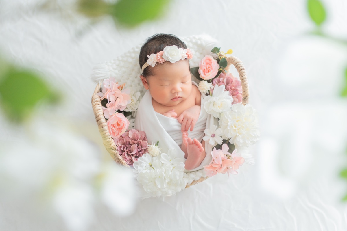 花かごの中でお花に囲まれて眠る新生児のニューボーンフォト