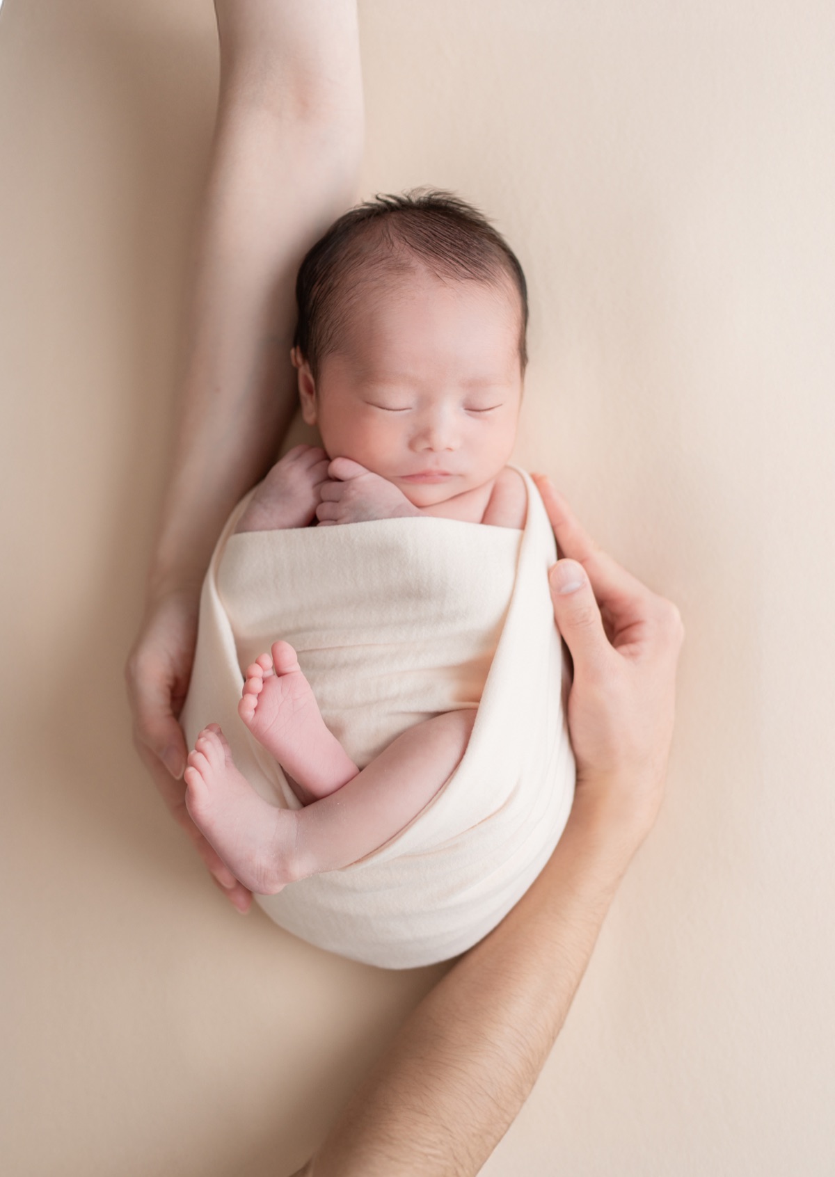 白いおくるみに包まれて眠る新生児のアップ