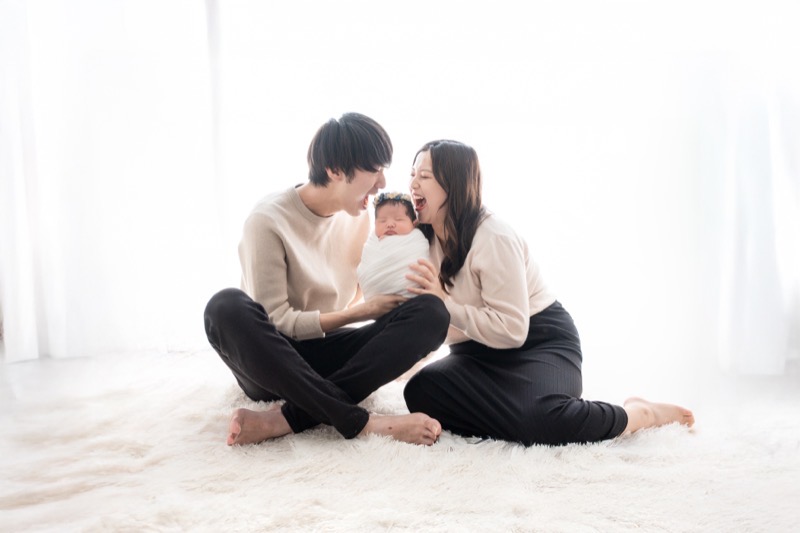 赤ちゃんを抱いて寄り添うパパとママの家族写真