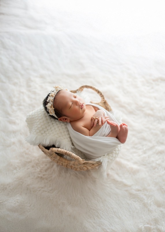 白いおくるみで丸くなって眠る新生児