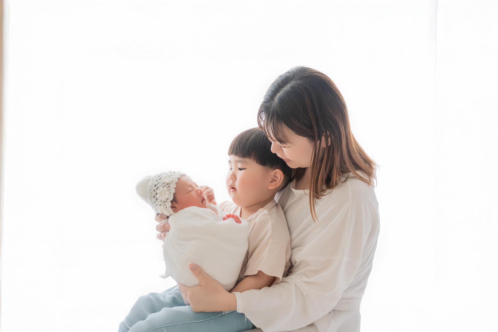 新生児を抱くママと寄り添うおねえちゃんの家族写真